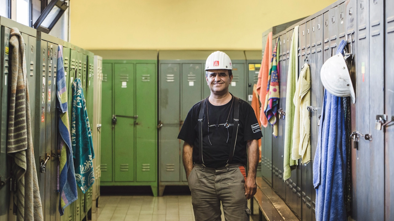 Betriebsrat Ayhan Yalgin steht im Umkleideraum der Gießerei DEUMU zwischen den Spinten der Arbeiter