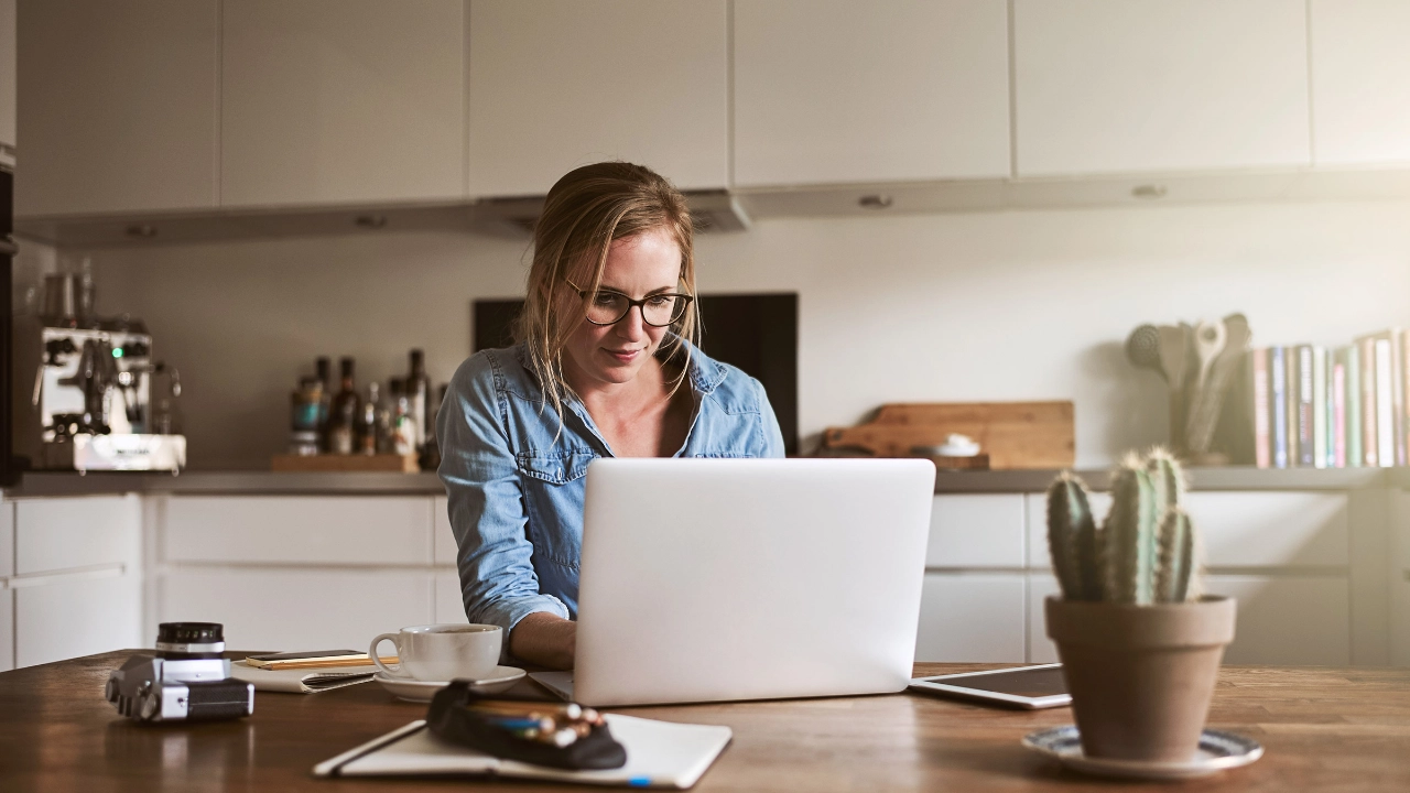 Junge Frau arbeitet in ihrer Küche mit einem Laptop