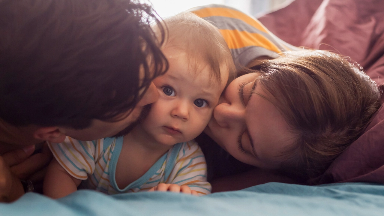 Eltern mit ihrem Kind liegen im Bett