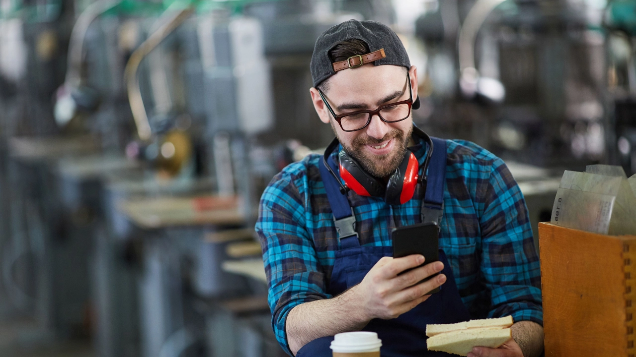 Arbeiter schaut während einer Pause auf sein Smartphone