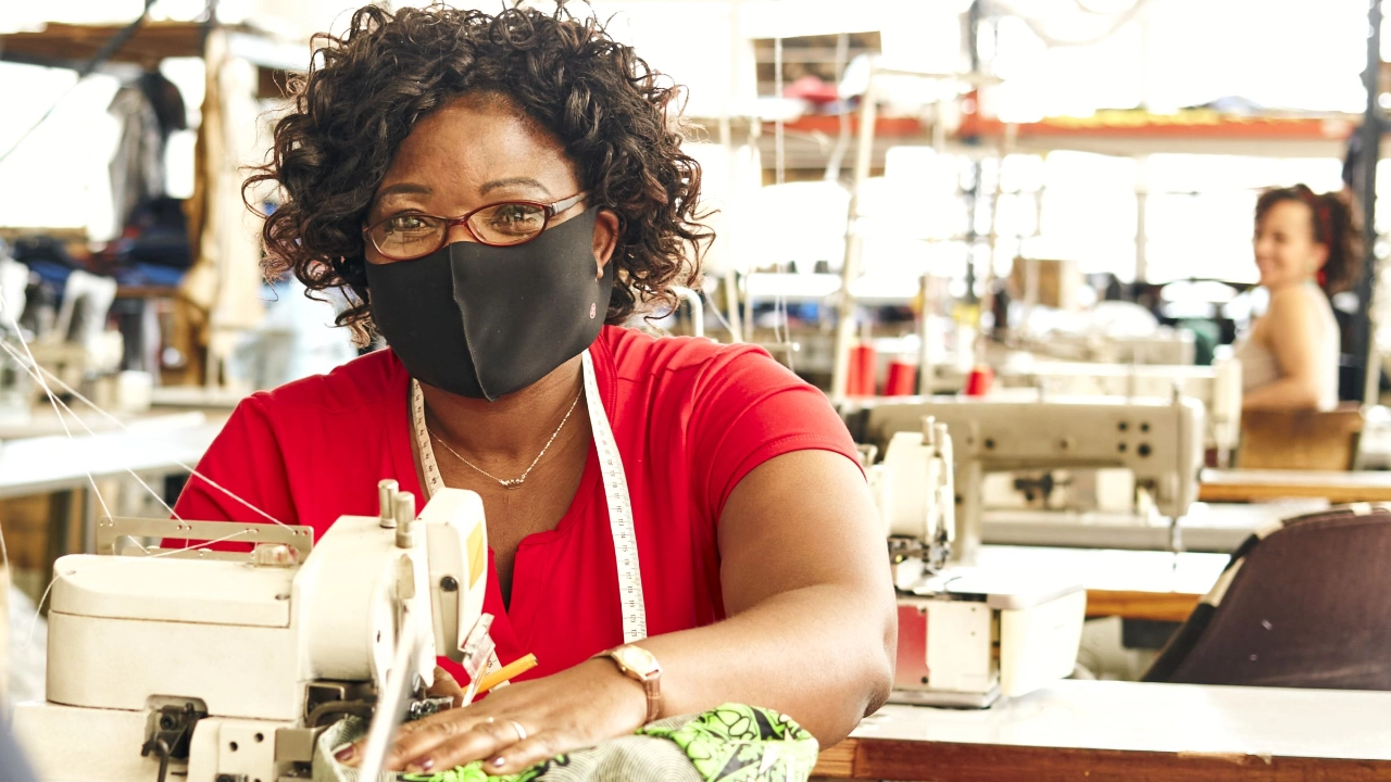 Näherin mit Maski in Textilfabrik 