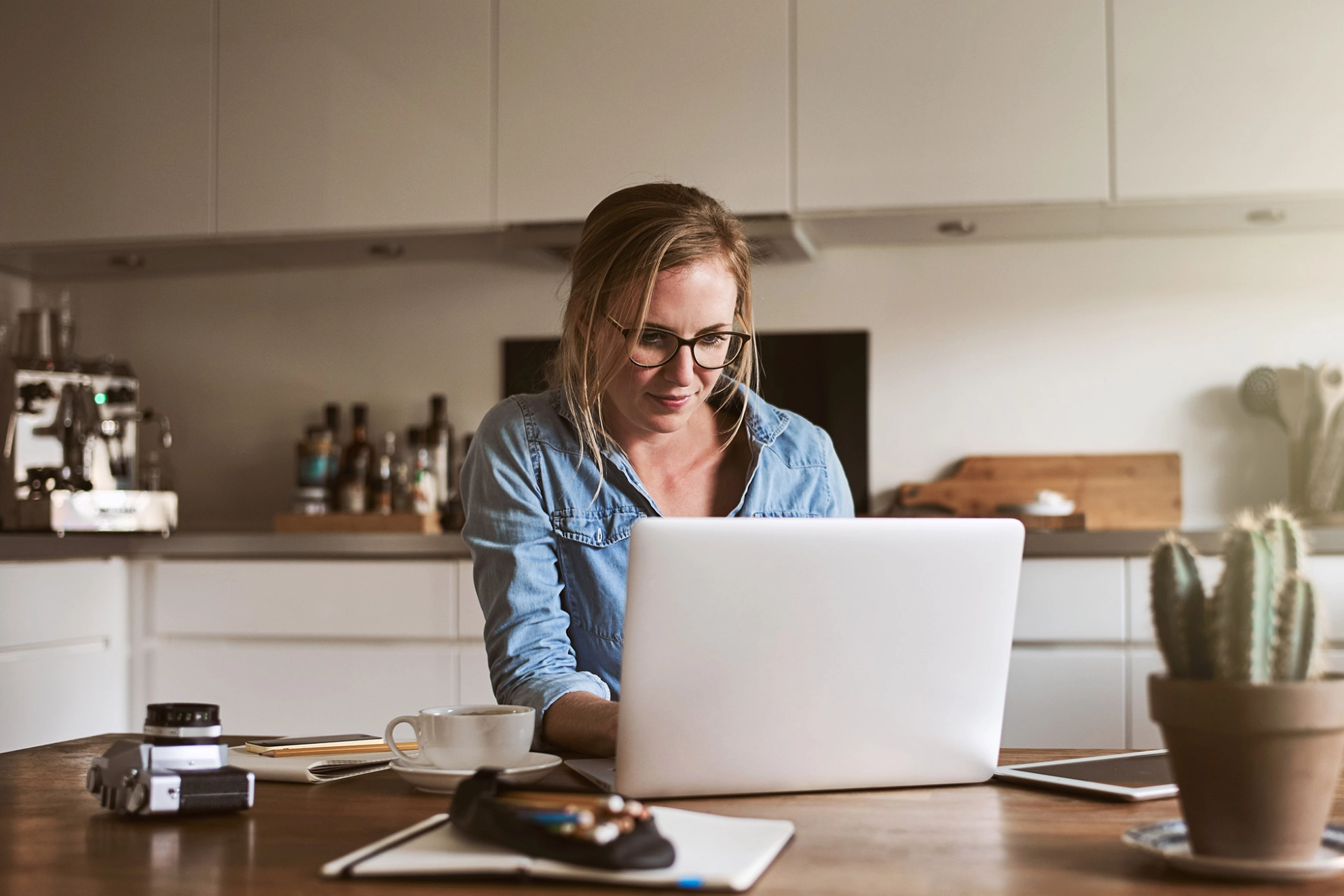 Junge Frau arbeitet in ihrer Küche mit einem Laptop