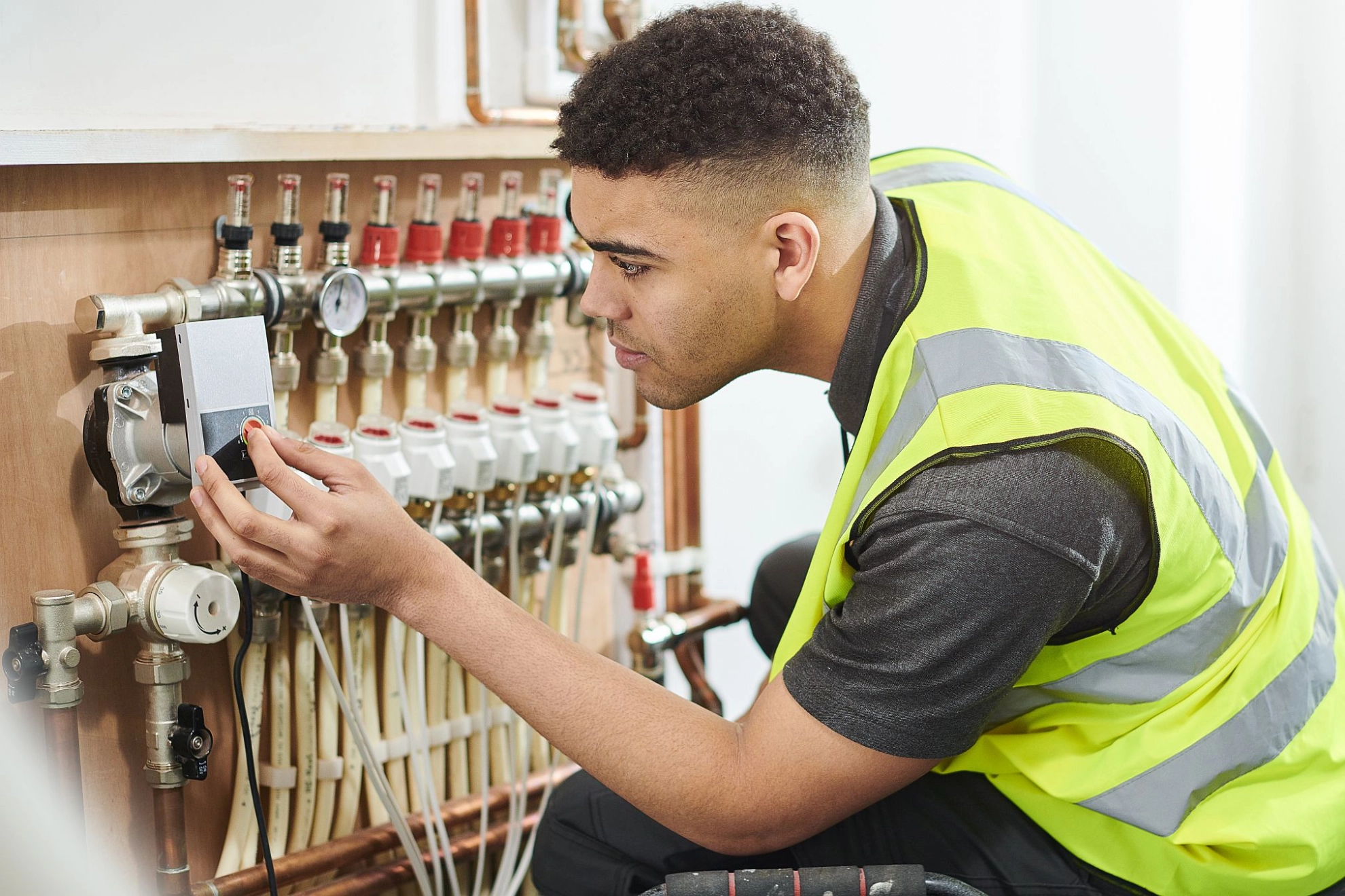 Auszubildender reguliert Messtechnik an Heizungsanlage