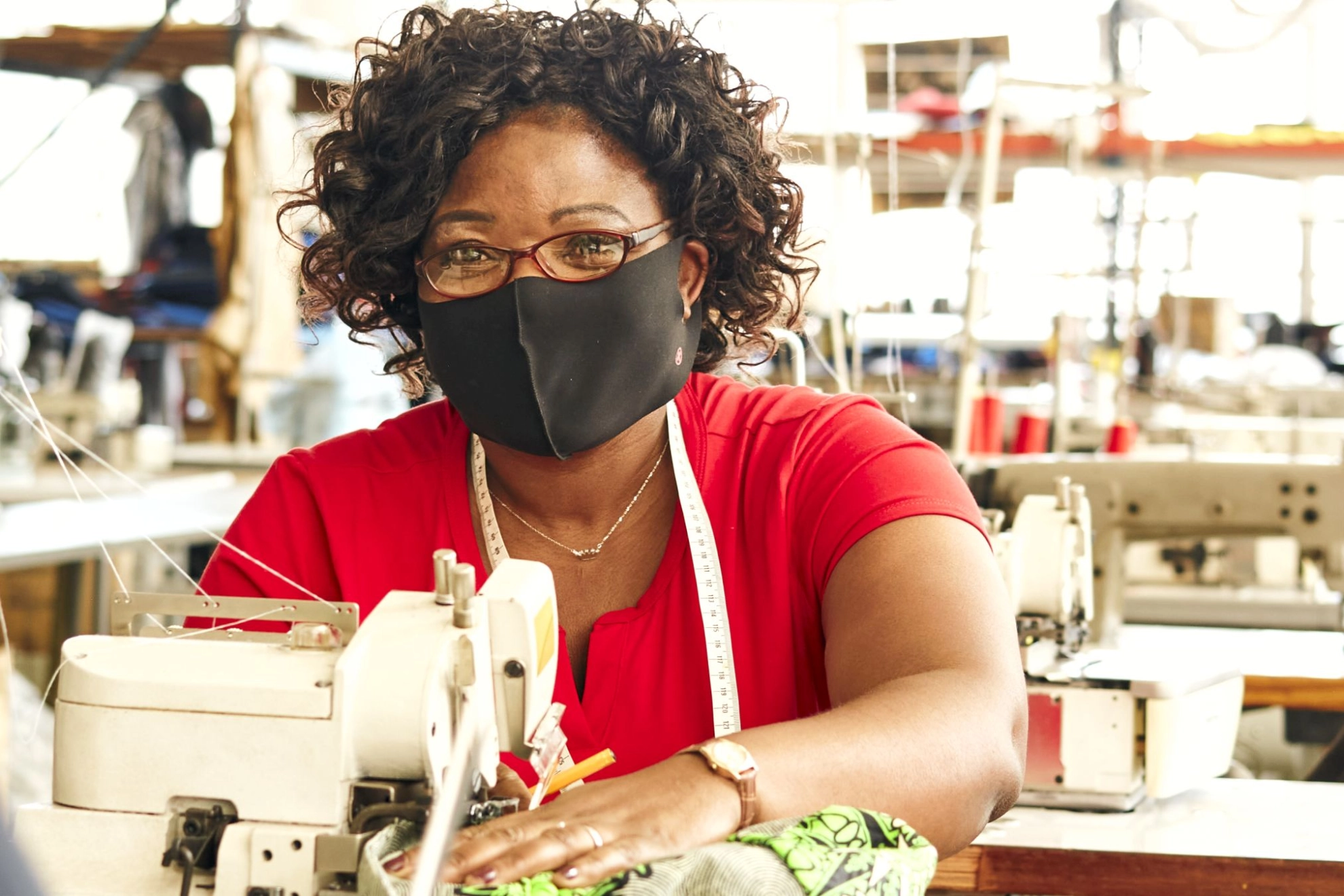 Näherin mit Maski in Textilfabrik 