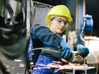 Junge Auszubildende schleift Schweißnähte in einer Werkstatt